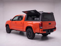 Lift-up side window open on the Toyota Tacoma truck cap, giving access to tool cases in the bed from beside the truck