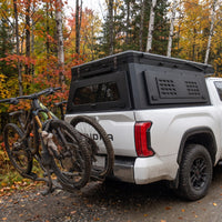 Toyota Tundra canopy camper closed, rear three-quarter view showing the locking MOLLE side panel and hitch bike rack