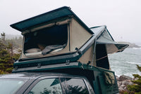 Front pop-up hatch open on the Double Pop-Up truck cap camper above a Toyota Tundra cab, with the bed made inside