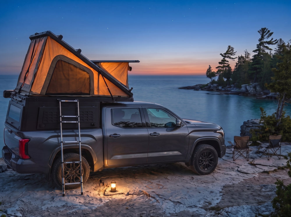 Toyota Tundra pop-up truck cap camper glowing at dusk on the Georgian Bay shore with camp chairs and a lantern