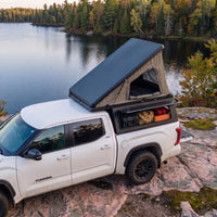 Toyota Tundra Single Pop-Up truck cap camper with the roof tent open beside a northern Ontario lake