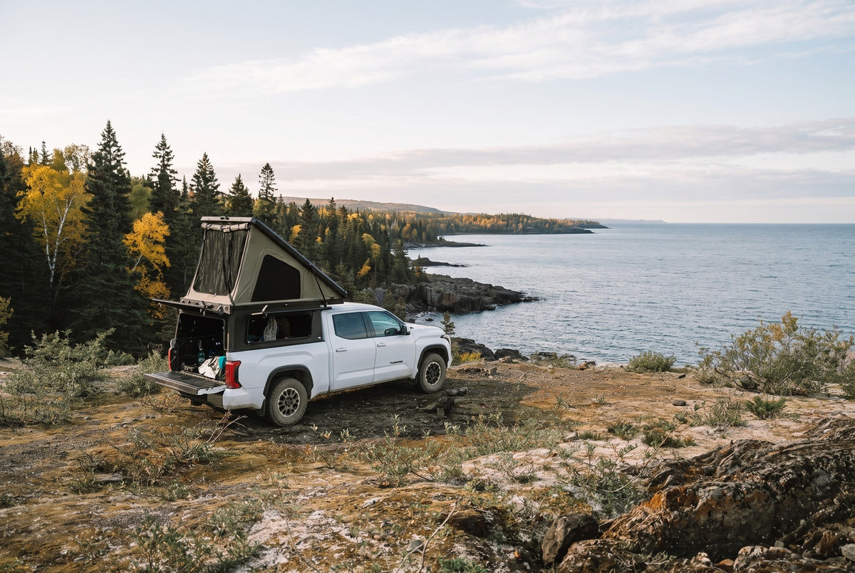 Wide view of a Toyota Tundra truck camper set up above the Lake Superior shoreline in autumn