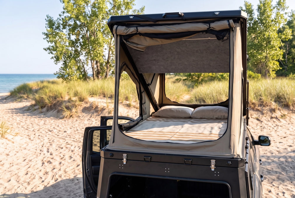 Rear view of the Toyota Tundra truck cap camper with the large rear tent window open and the bed made, on a Lake Huron beach