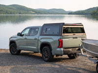 Toyota Tundra with a windowed truck cap towing an aluminum fishing boat at a boat launch