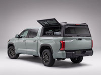 Lift-up side window open on the Toyota Tundra truck cap, giving access to tool cases in the bed from beside the truck