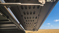 Underside of the raised side hatch showing the laser-cut MOLLE panel, hinges and gas struts
